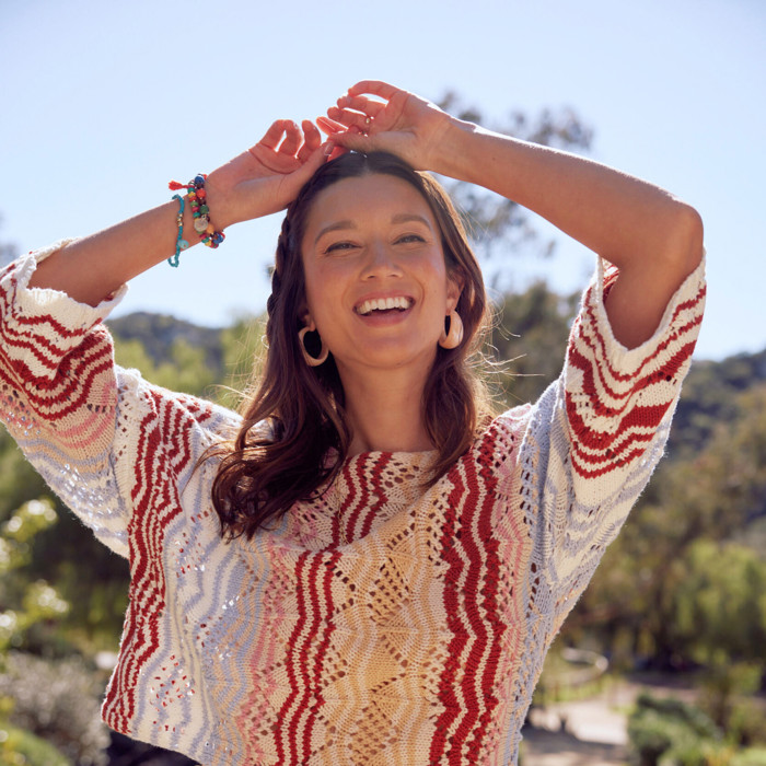 Smiling model wearing a colorful sweater outside