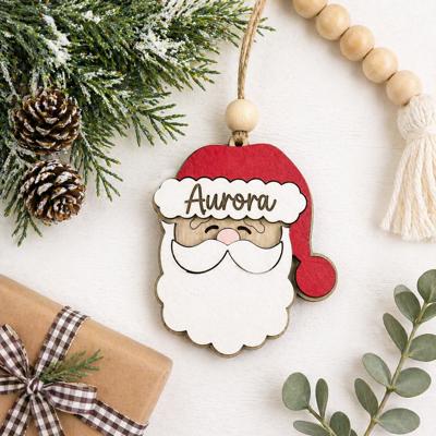 Personalized Santa Claus Ornament  Size: 4''X4.5''  This ornament is laser cut with two layer giving the ornament a 3D look, the name is engraved  It arrives ready to hang with twine string and one wo