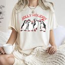  Jolly Holiday Penguins Christmas Parade In Cozy Winter Village Scene With Snowflakes And Cheer Comfort Colors Tee