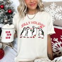  Jolly Holiday Penguins Christmas Parade In Cozy Winter Village Scene With Snowflakes And Cheer Comfort Colors Tee