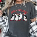 Large Pepper Dark Gray Jolly Holiday Penguins Christmas Parade In Cozy Winter Village Scene With Snowflakes And Cheer Comfort Colors Tee